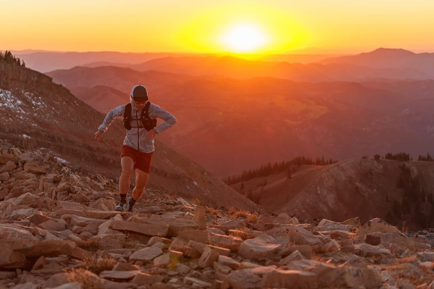 Trail runner ascending a rocky ridge at golden hour in the Tetons